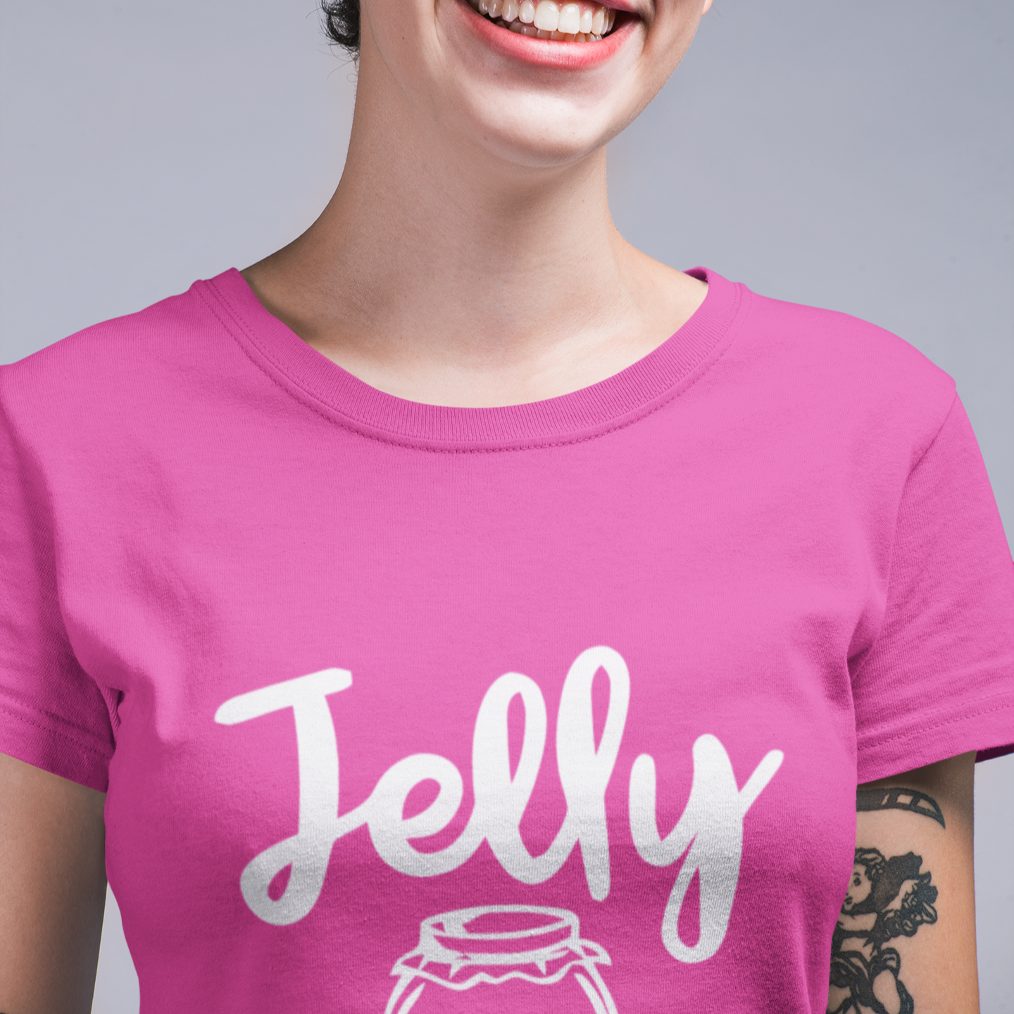 Person wearing a pink t-shirt with 'Jelly' printed on it against a gray background