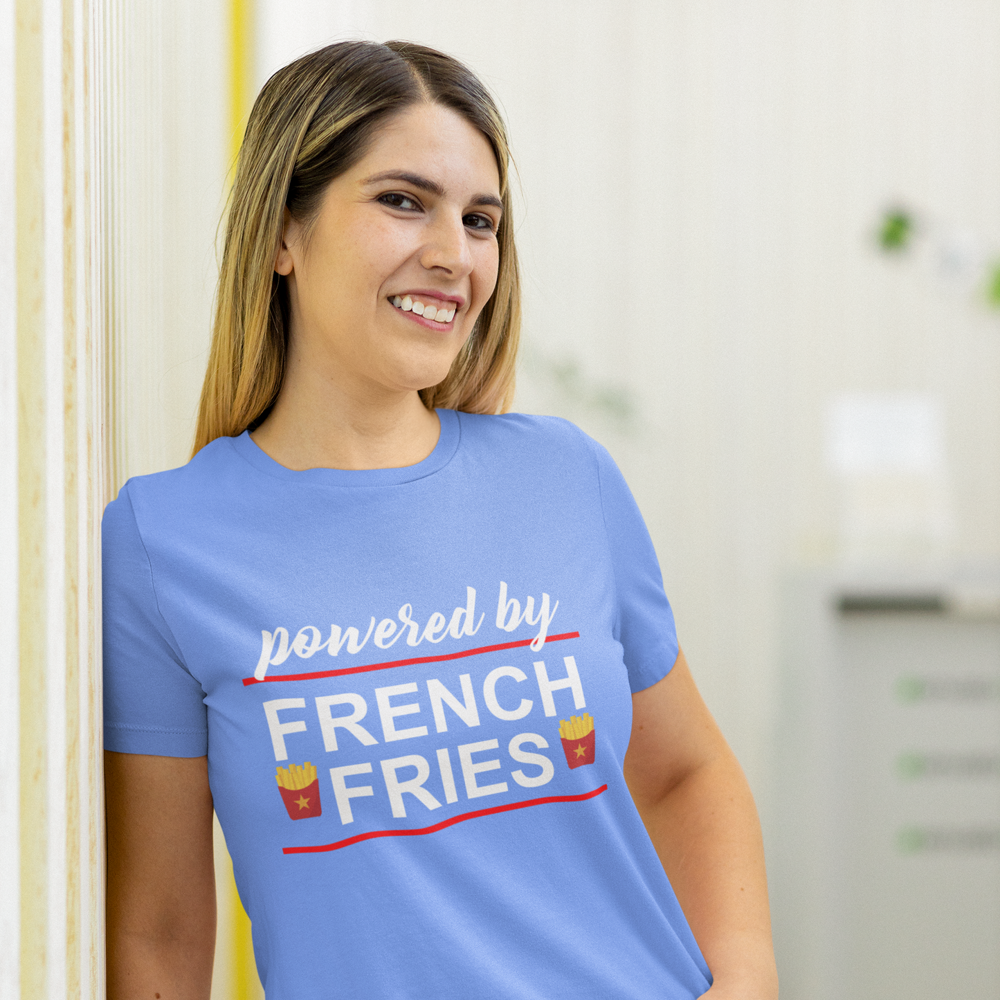 Woman wearing a blue t-shirt with 'Powered by French Fries' text, standing indoors.