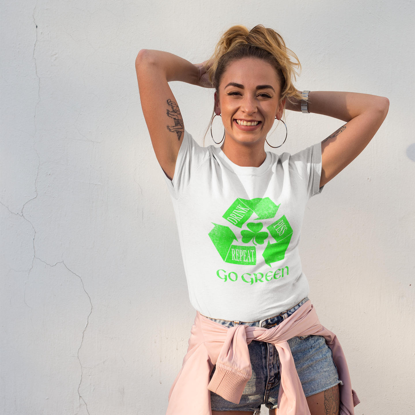 Woman wearing a white t-shirt with a green recycling symbol and text, standing against a light gray background.