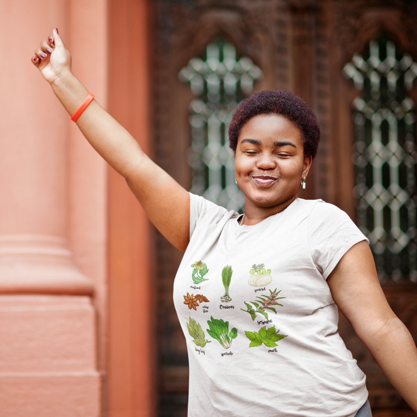Woman wearing a white t-shirt with plant illustrations in front of a decorative wall.