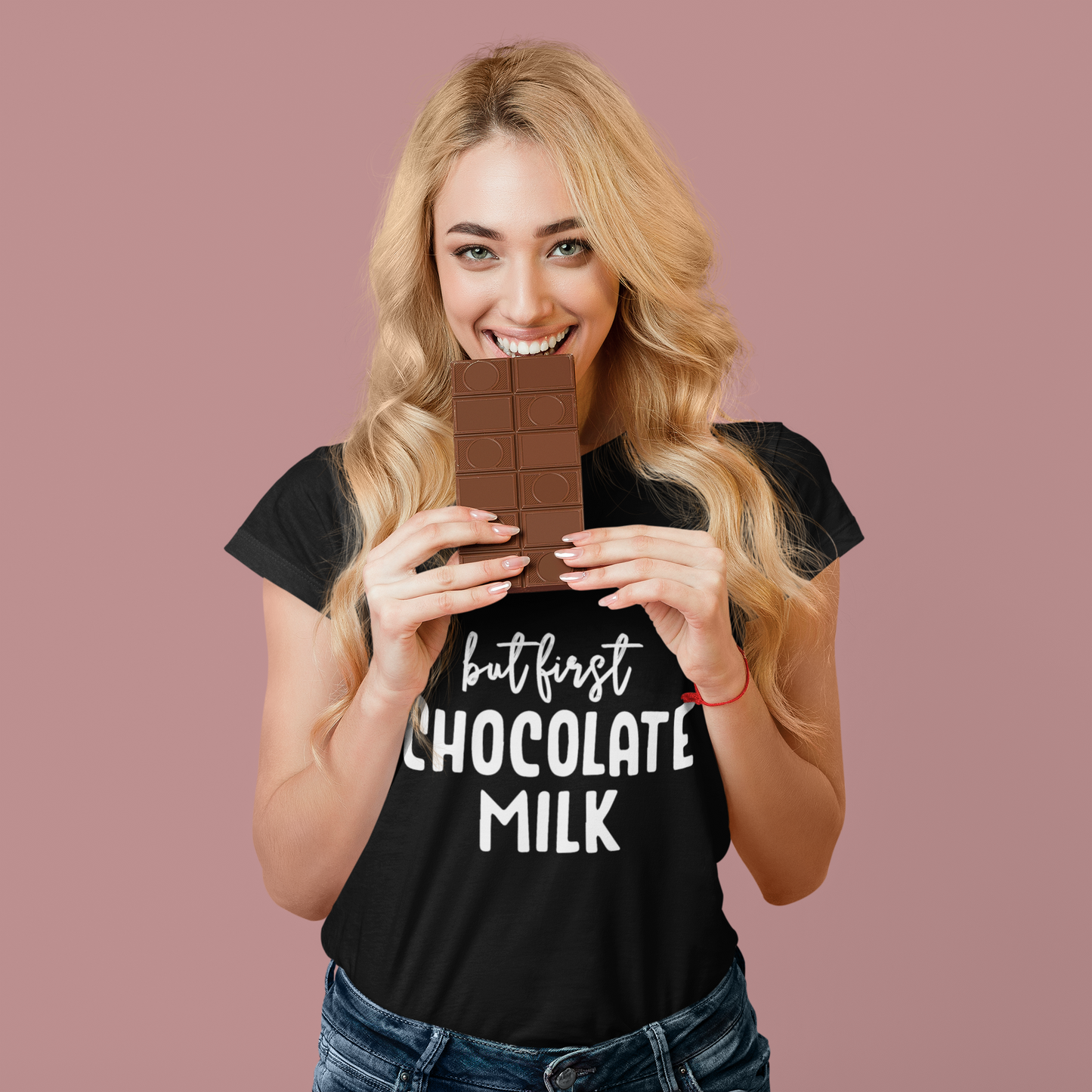 Woman holding a chocolate bar wearing a black t-shirt with 'but first Chocolate Milk' text on a pink background