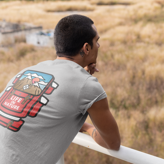 Man wearing a t-shirt with a nature graphic, standing on a balcony overlooking a field.