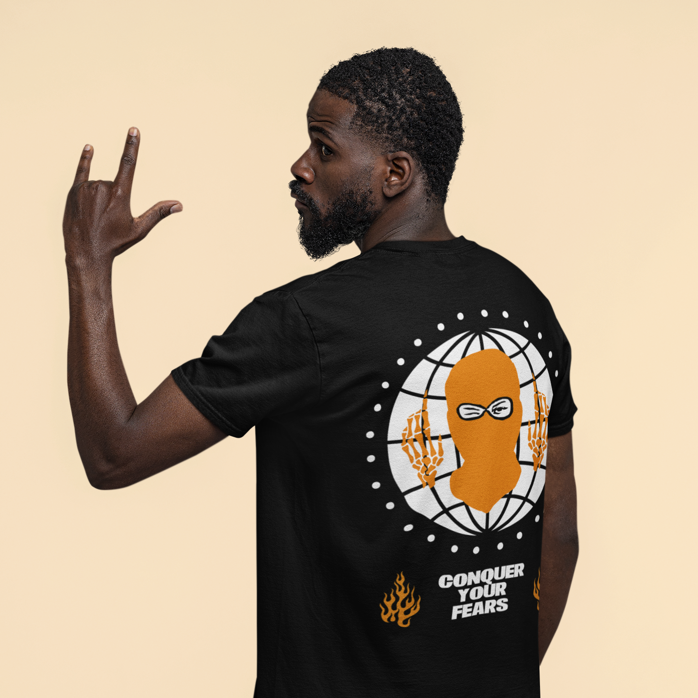 Person wearing a black t-shirt with a graphic design and text on the back, against a beige background