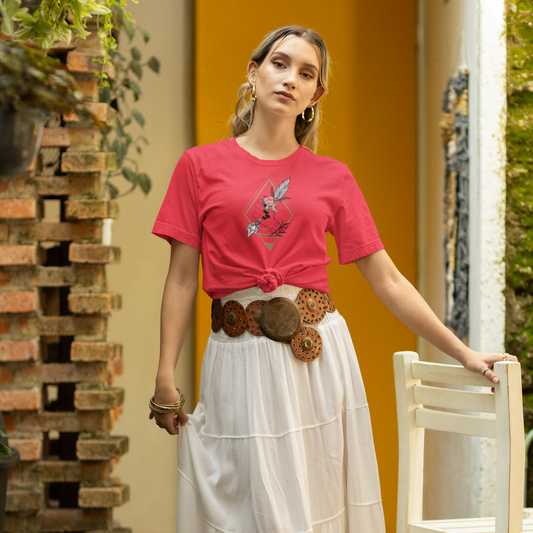 Woman wearing a red shirt and white skirt standing outdoors with a chair and yellow wall in the background.