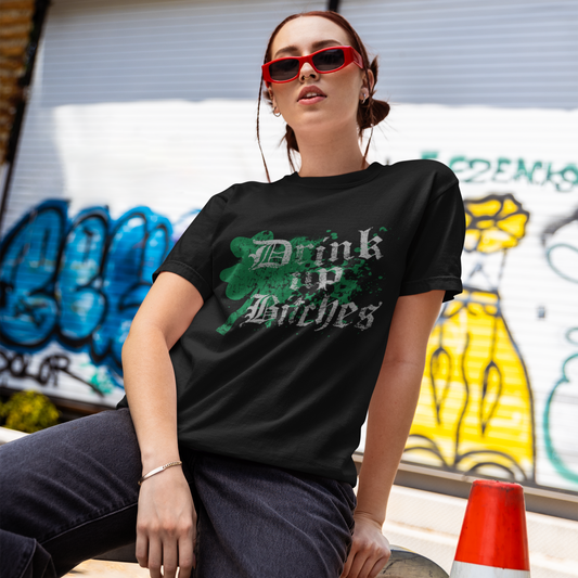 Person wearing a black t-shirt with text, sitting against a graffiti-covered wall.