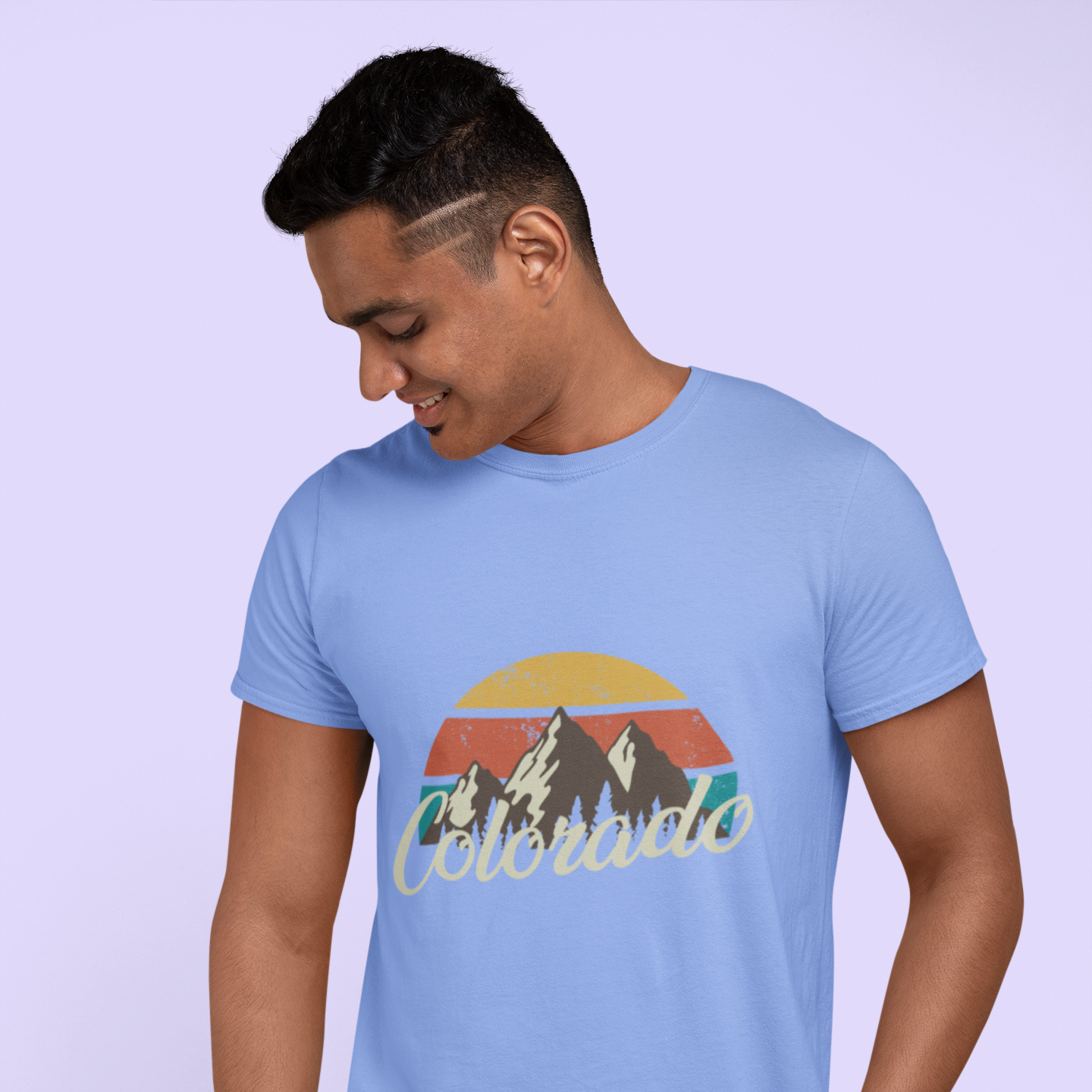 Person wearing a light blue t-shirt with a mountain graphic and 'Colorado' text on a light purple background