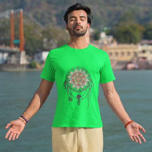 Man wearing a green t-shirt with a design standing by a body of water with mountains in the background.