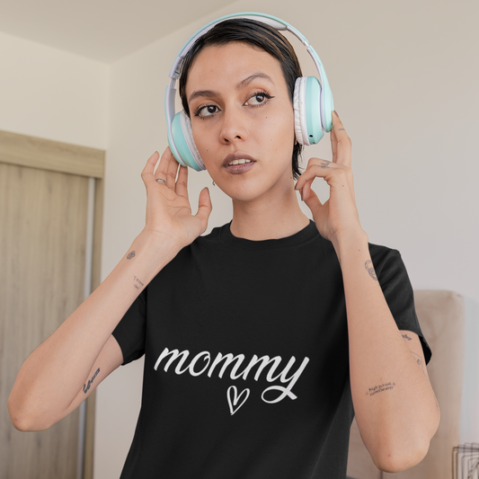 Person wearing a black t-shirt with 'mommy' text and light blue headphones indoors.