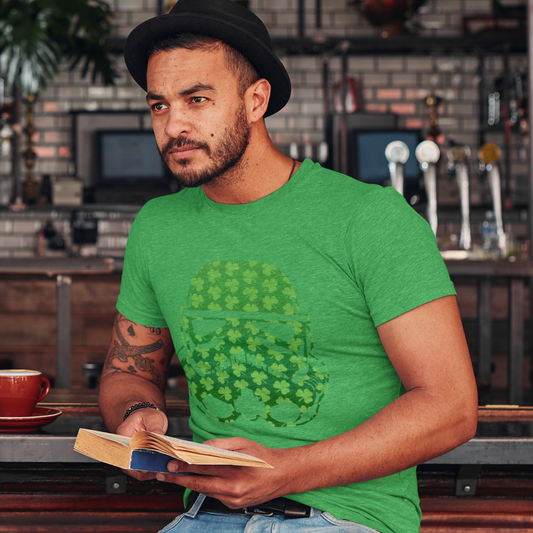 Man in a green t-shirt with a graphic design, holding a book, sitting at a bar.