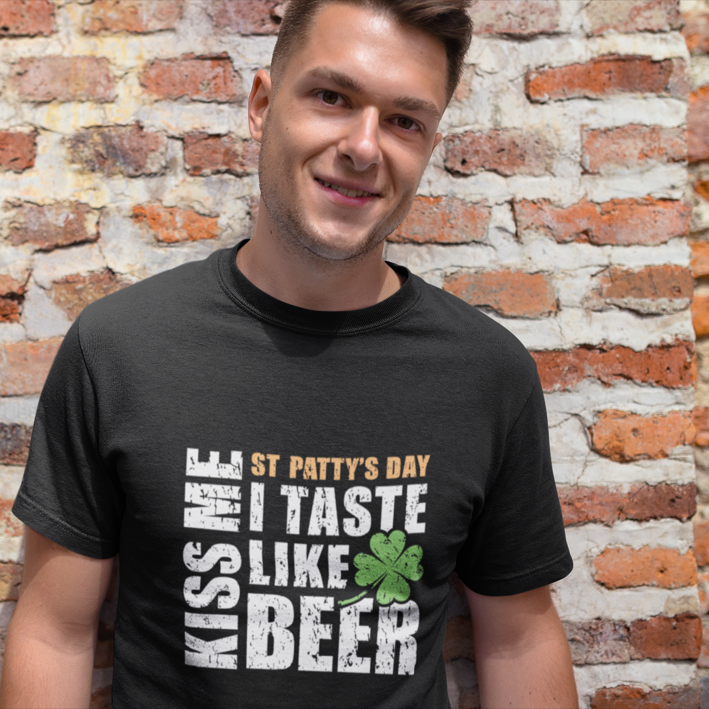 Man wearing a black t-shirt with St. Patrick's Day text design against a brick wall.