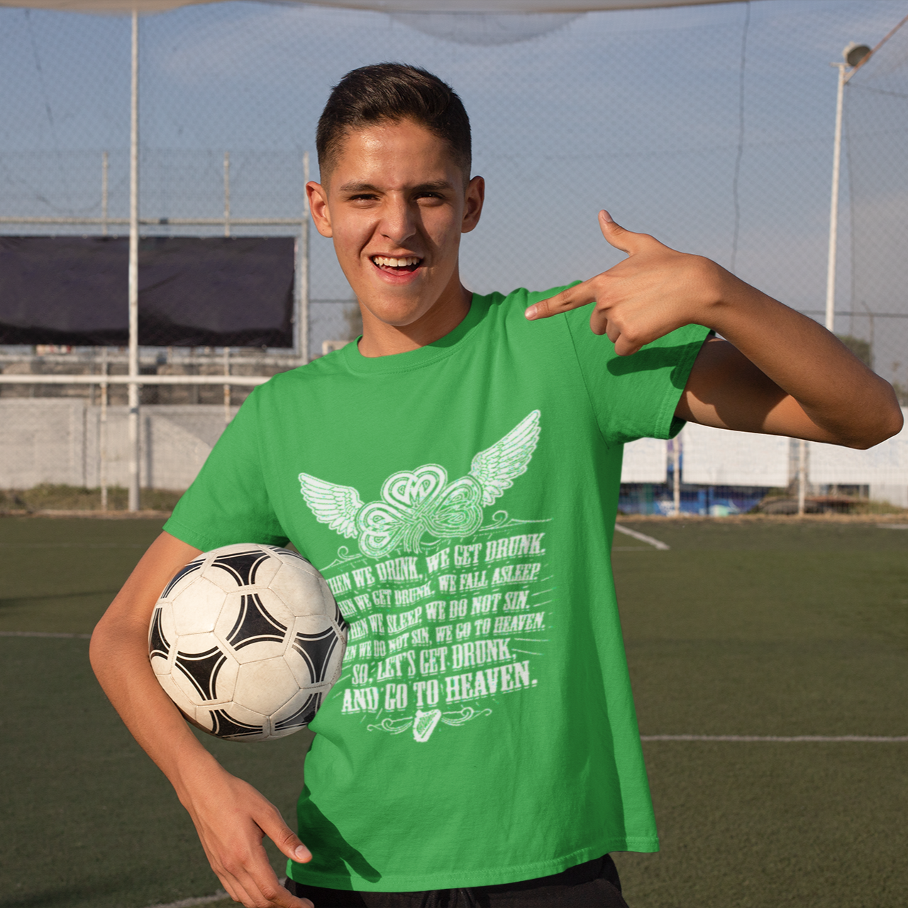 Person wearing a green t-shirt with a soccer ball on a sports field