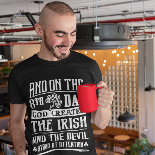 Man wearing a black t-shirt with text holding a red mug in an indoor setting.