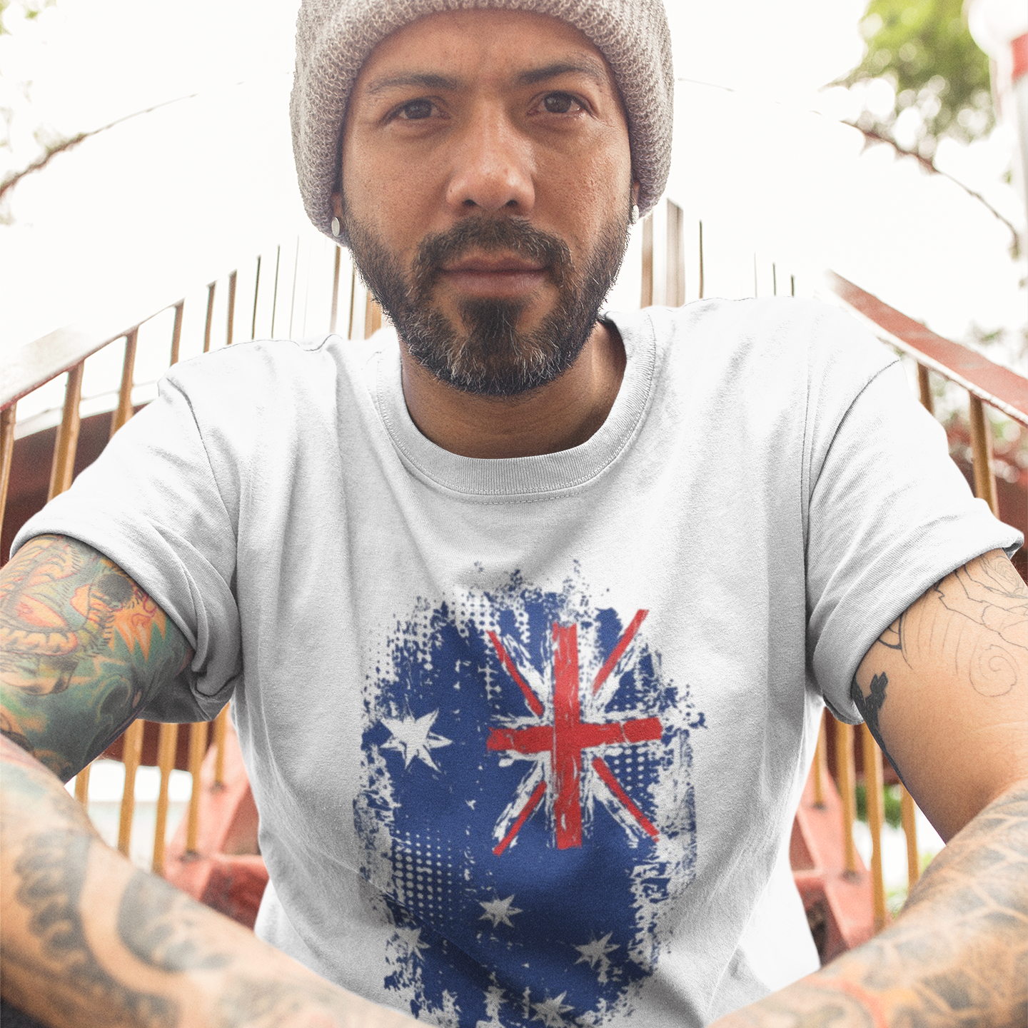 Man wearing a t-shirt with an Australian flag design, sitting outdoors.