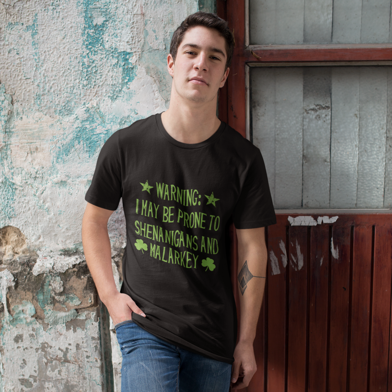 Person wearing a black t-shirt with text standing against a textured wall.