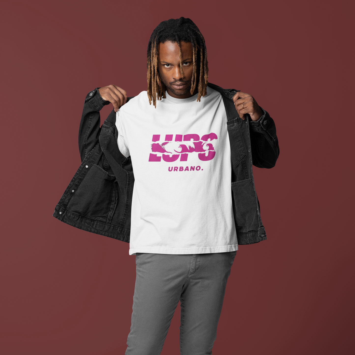 Man wearing a white t-shirt with pink text, gray pants, and white shoes on a maroon background