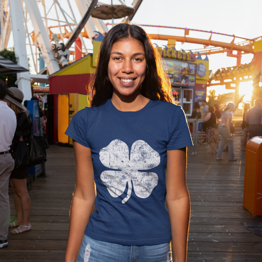 Woman wearing a blue t-shirt with a white shamrock design at an amusement park.