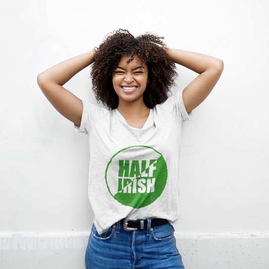 Person wearing a white t-shirt with a green graphic and text, standing against a white wall.