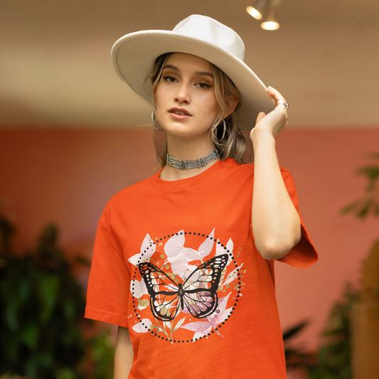 Person wearing an orange t-shirt with a butterfly design, standing indoors.