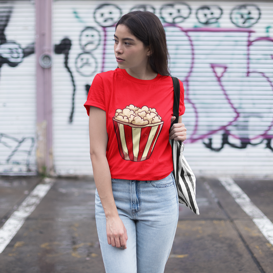 Woman wearing a red t-shirt with a popcorn design in front of a graffiti-covered wall.
