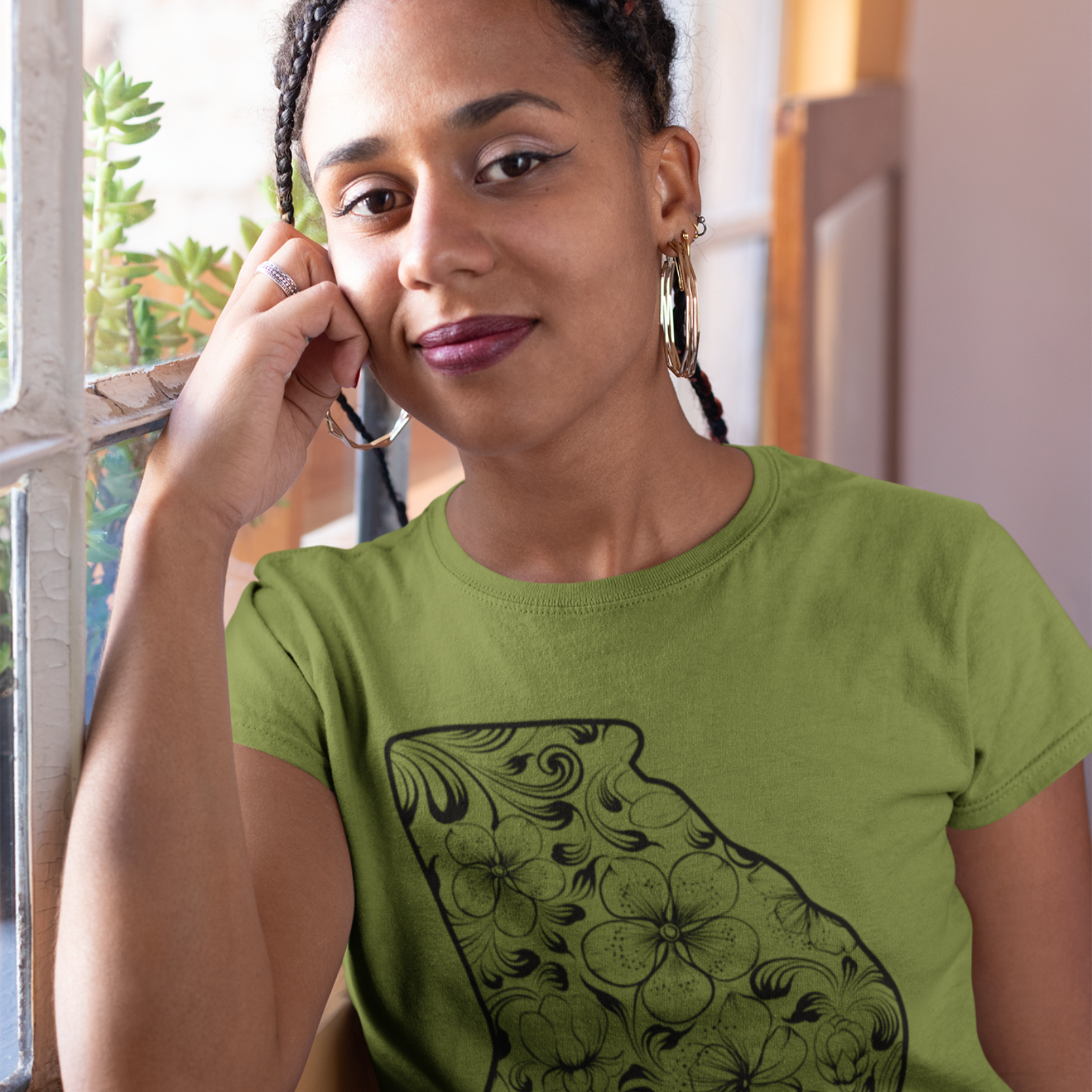 Woman wearing a green t-shirt with a floral design, standing indoors.
