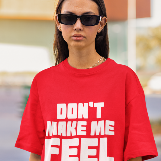 Person wearing a red t-shirt with text 'DON'T MAKE ME FEEL BORING' outdoors.