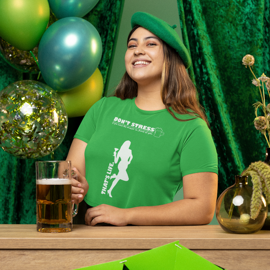Person wearing a green shirt with a graphic design, sitting at a table with green decorations and balloons.