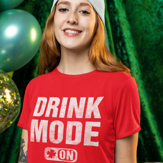 Person wearing a red 'DRINK MODE ON' t-shirt holding a beer mug with a festive background.