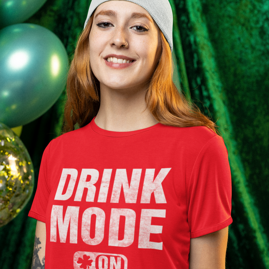 Person wearing a red 'DRINK MODE ON' t-shirt holding a beer mug with a festive background.