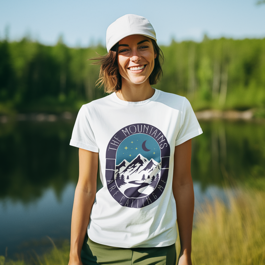 Woman wearing a white t-shirt with a mountain design by a lake