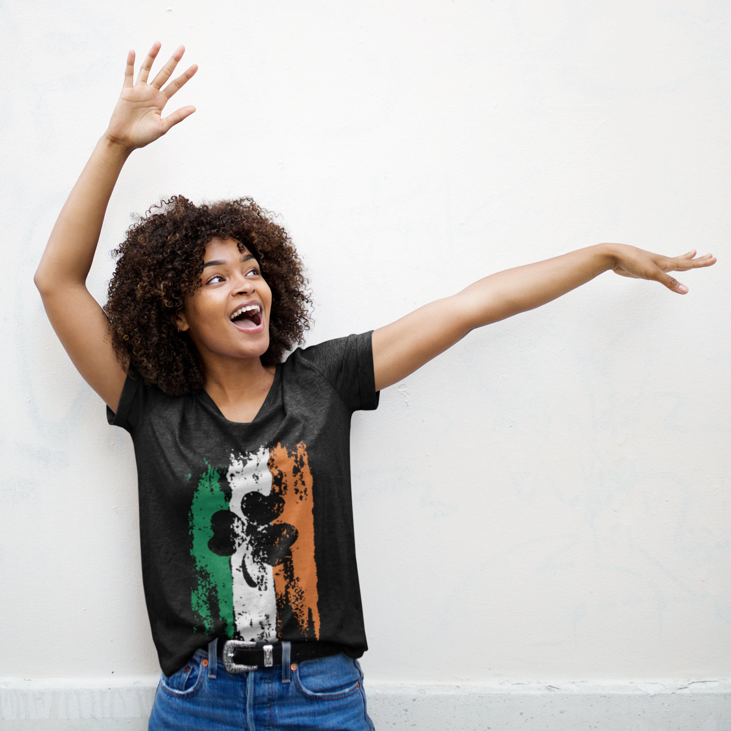 Woman wearing a black t-shirt with a colorful graphic design, standing against a white wall.