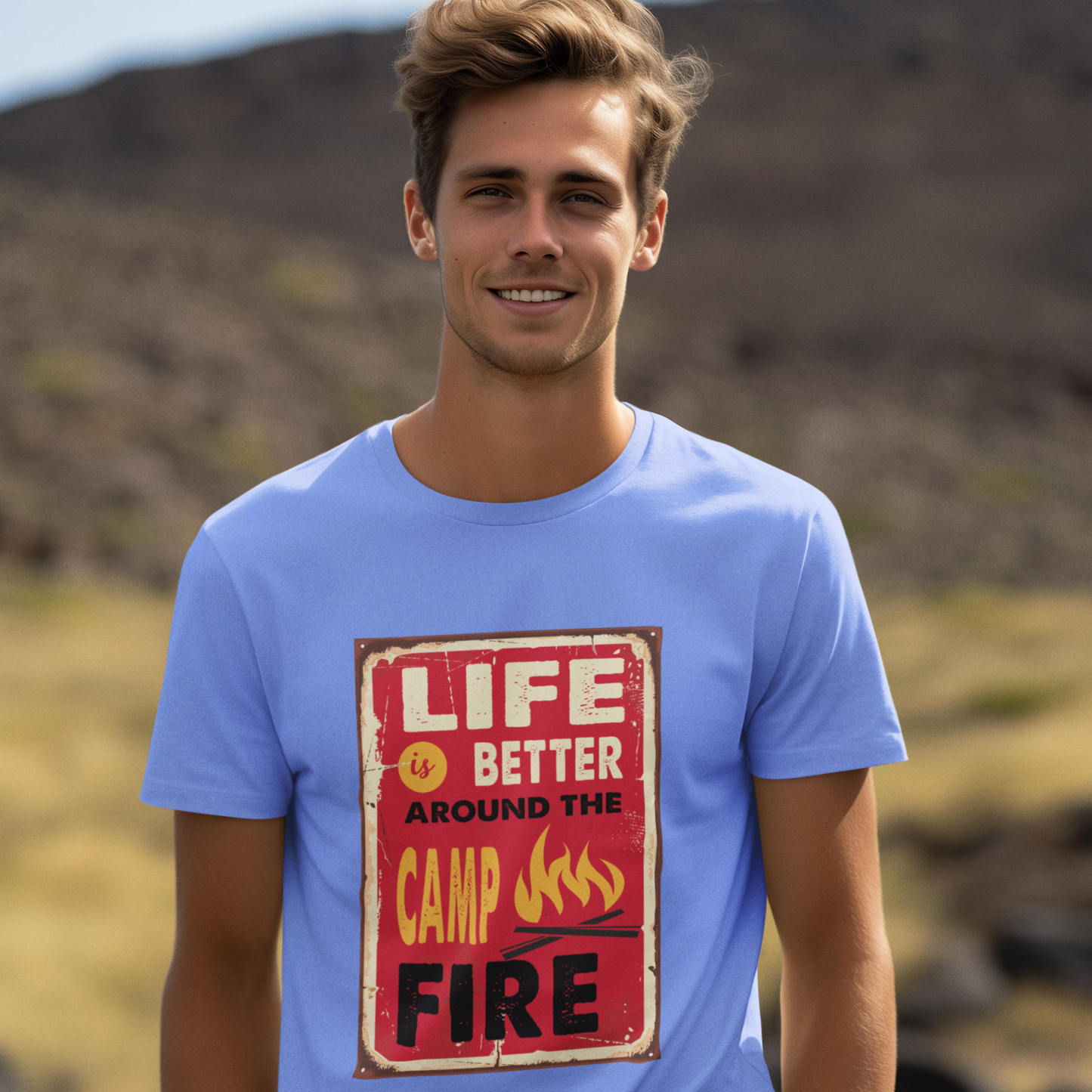 Man wearing a blue t-shirt with a campfire-themed design outdoors.