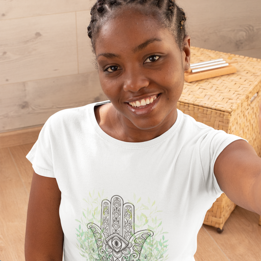 Woman wearing a white t-shirt with a henna design, sitting on a wooden floor.