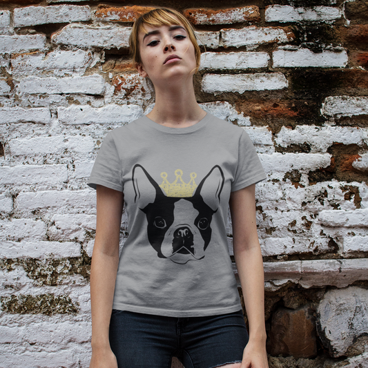 Woman wearing a gray t-shirt with a dog graphic against a textured brick wall.