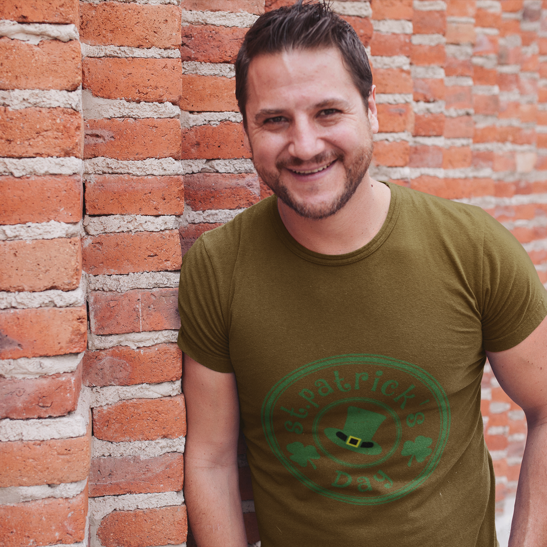 Man wearing a green t-shirt with a logo against a brick wall