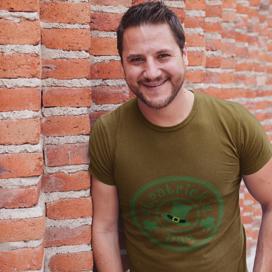 Man wearing a green t-shirt with a logo against a brick wall
