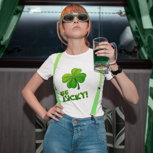 Person wearing a 'Be Lucky!' shirt with a green shamrock, holding a glass of green beer.