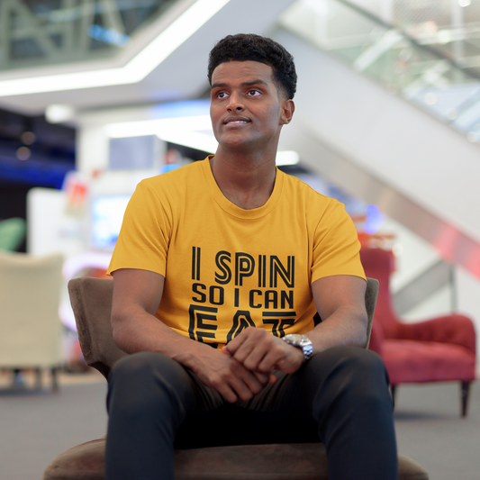 Man wearing a yellow t-shirt with text sitting in a modern indoor setting