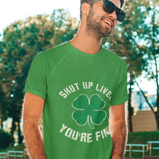 Man wearing a green t-shirt with a shamrock design and text outdoors.