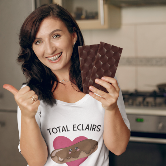 Woman holding chocolate bars in a kitchen wearing a shirt with 'Total Eclairs' text.