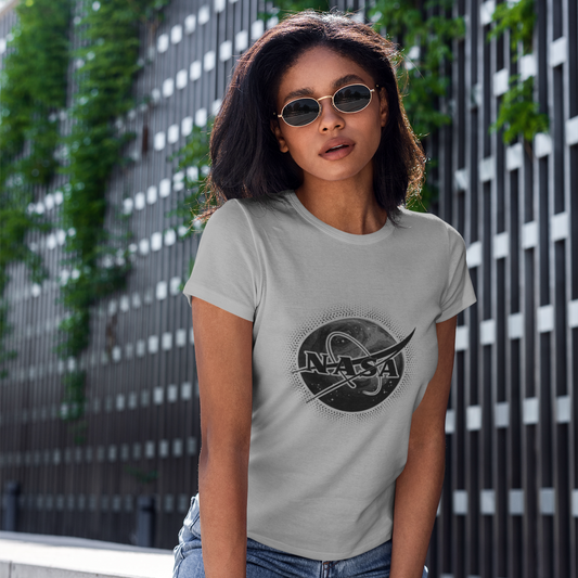 Woman wearing a gray t-shirt with a graphic design, standing against an urban wall background.