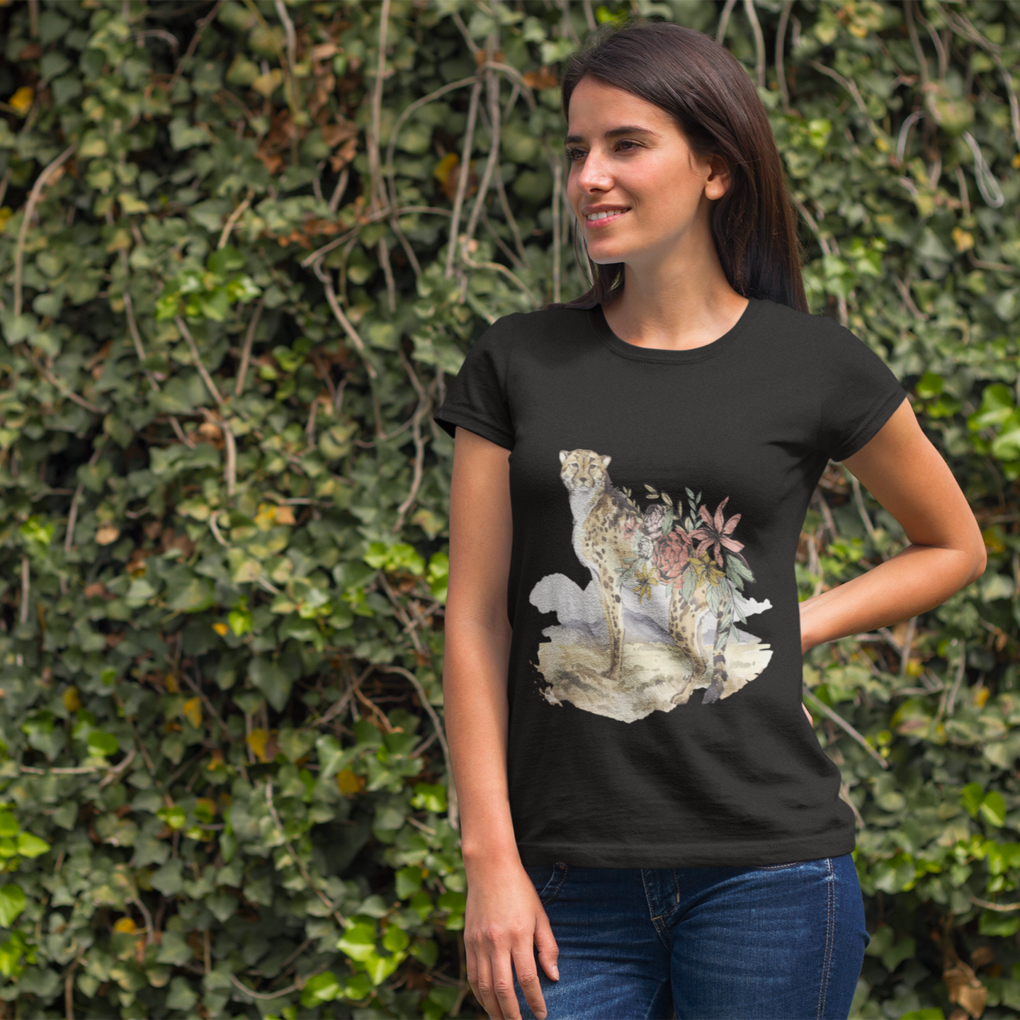 Woman wearing a black t-shirt with a graphic design in front of a green leafy background