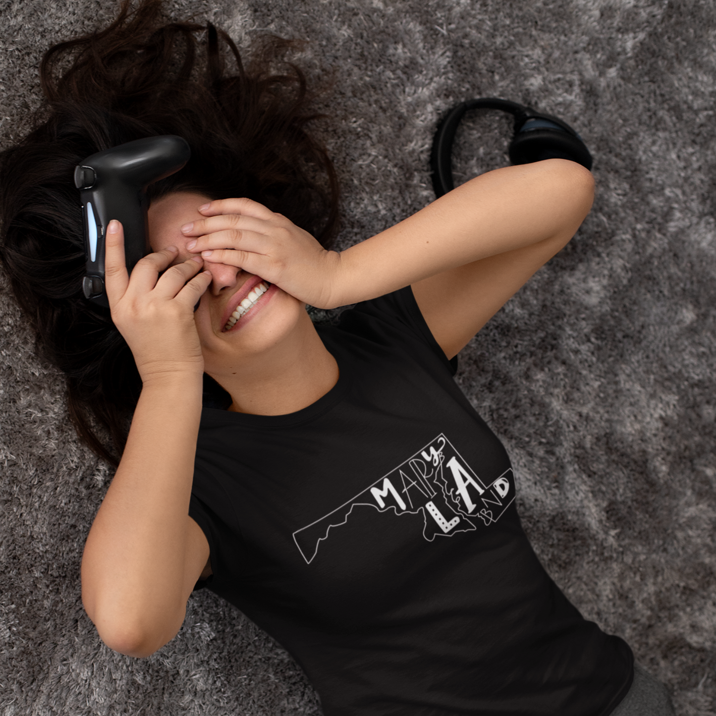 Person wearing a black t-shirt with a graphic design, lying on a textured gray surface.