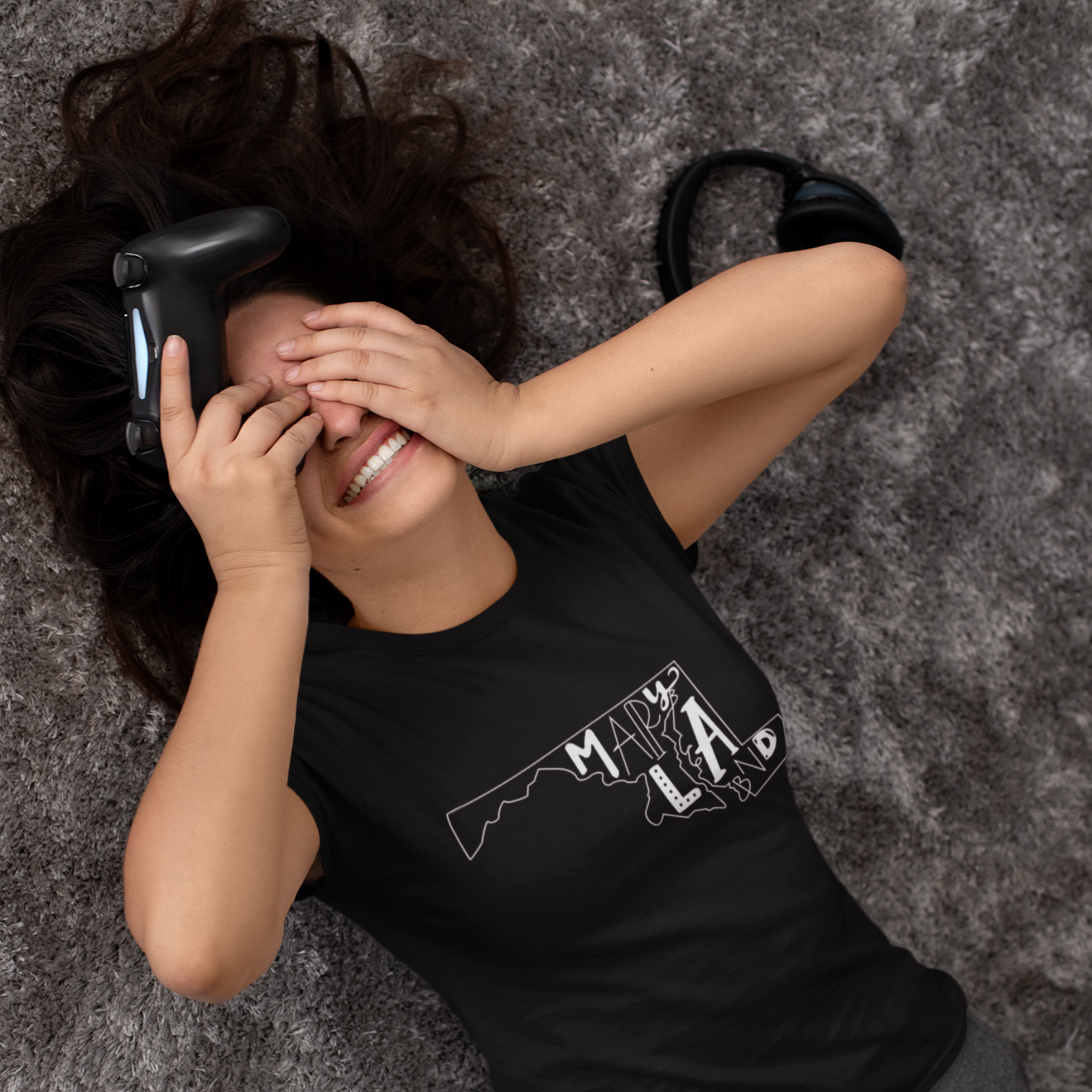 Person wearing a black t-shirt with a graphic design, lying on a textured gray surface.