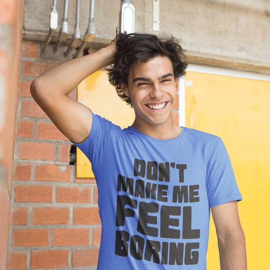 Person wearing a blue t-shirt with text, standing against a yellow wall and brick wall.