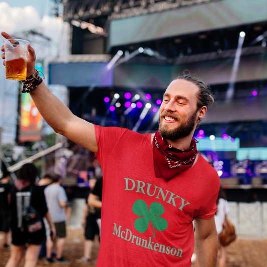 Man in a red 'DRUNKY McDrunkenson' shirt holding a beer at a concert.
