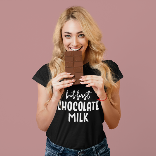 Woman holding a chocolate bar wearing a black t-shirt with 'but first Chocolate Milk' text on a pink background