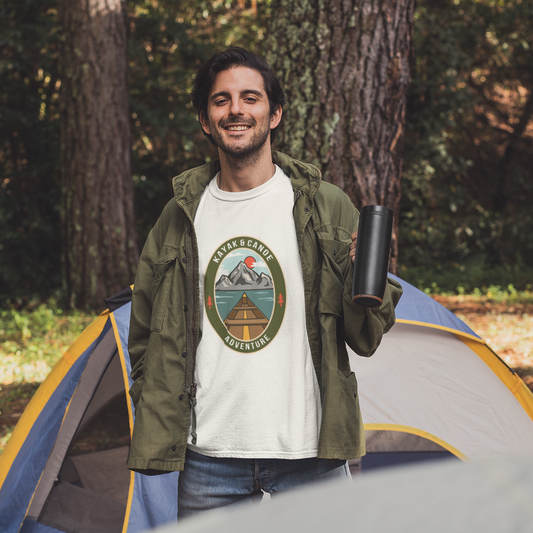 Man standing in front of a tent wearing a white t-shirt with a logo, surrounded by trees.