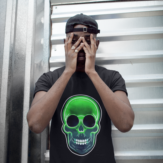 Person wearing a black t-shirt with a green skull design, covering their face against a metallic background.