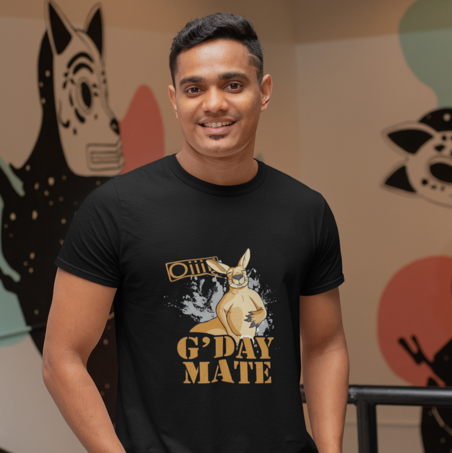 Man wearing a black t-shirt with a kangaroo graphic and text, standing in front of a colorful wall.