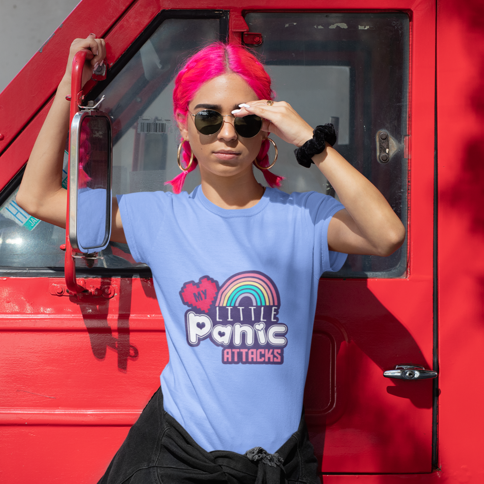 Person wearing a blue t-shirt with a colorful graphic design, standing next to a red vehicle.